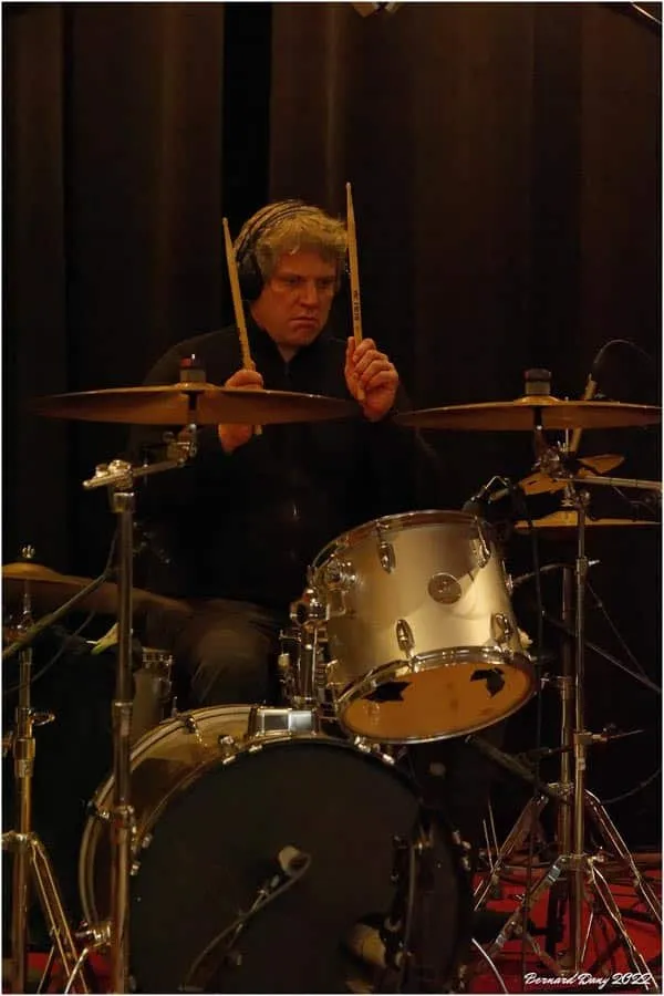 Le batteur du groupe, baguettes levées, pendant l’enregistrement