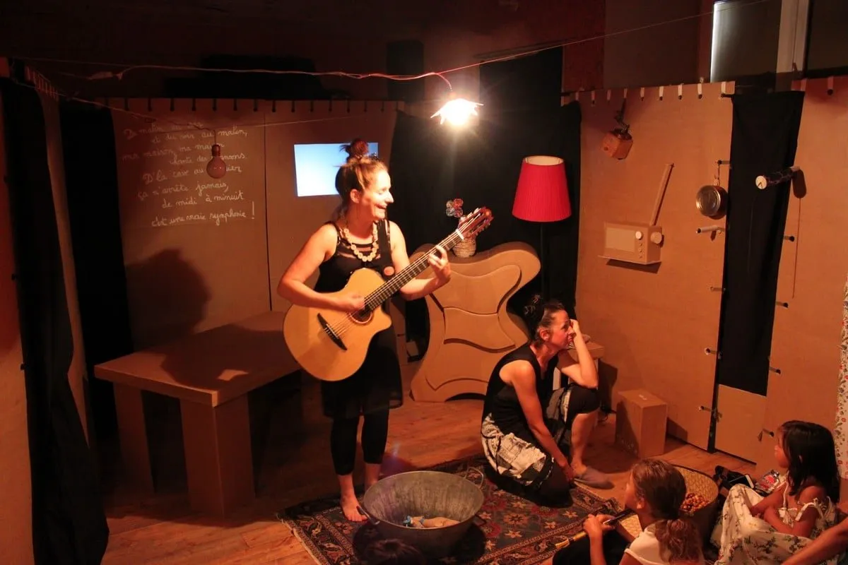 Une comédienne joue de la guitare devant les enfants