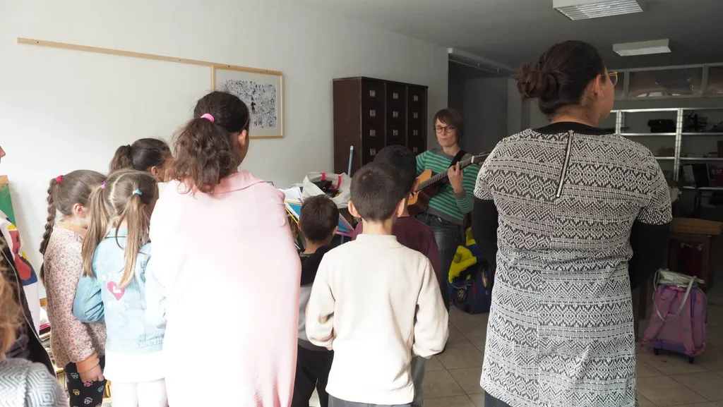 Un groupe d’enfants, vus de dos, face aux intervenantes pendant la répétition