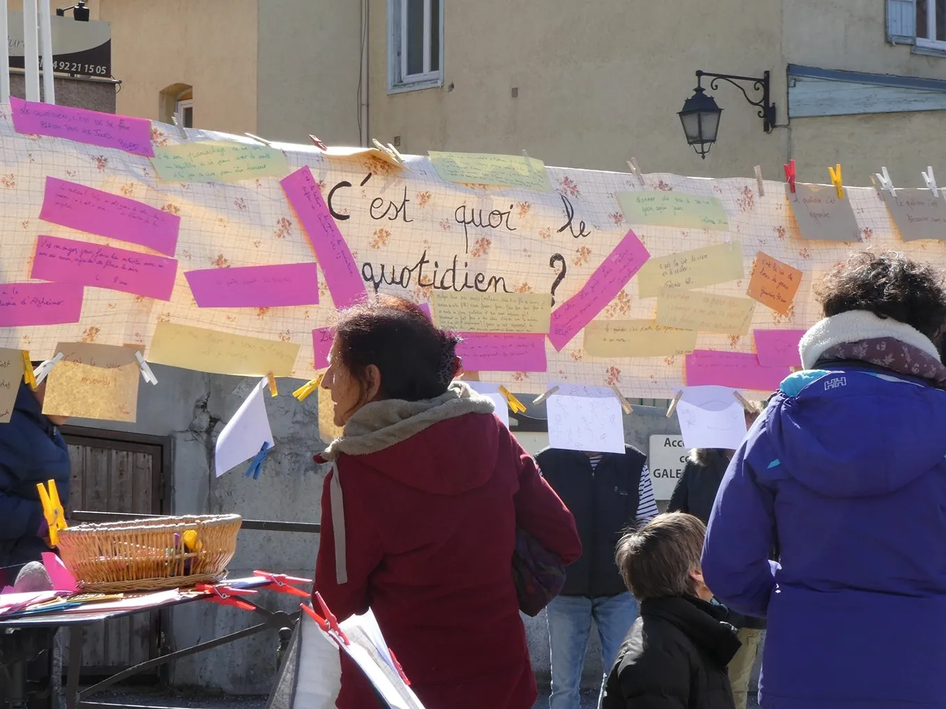 Des passants devant une grande banderole couverte de papiers de couleur